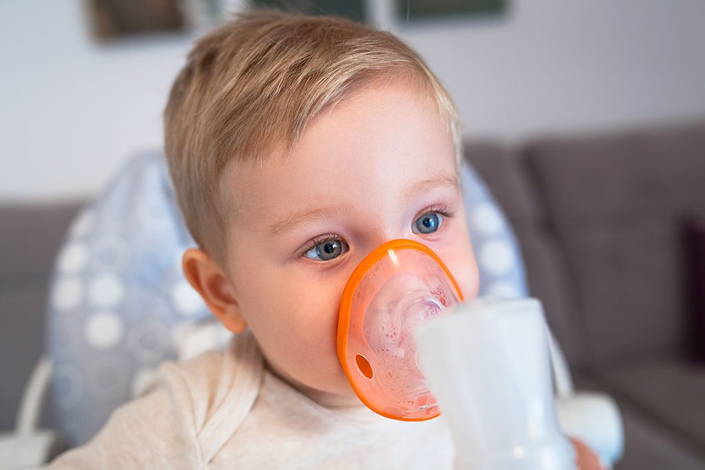 Little boy taking inhalation therapy by the mask of a nebuliser