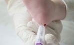 Infirmière prélevant une goutte de sang au talon d'un nouveau-né pour le dépistage néonatal